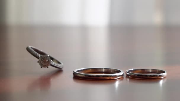 Wedding rings jewelry. Three gold rings on wooden background table. — Stockvideo