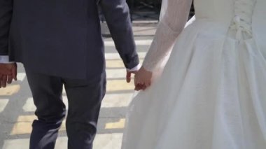 Gelin ve damat şehirde yürüyor. Düğün çifti el ele tutuşuyor..