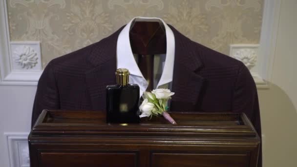 Askıda siyah erkek kıyafeti. Ceket, pantolon, yaka çiçeği ve parfüm.. — Stok video