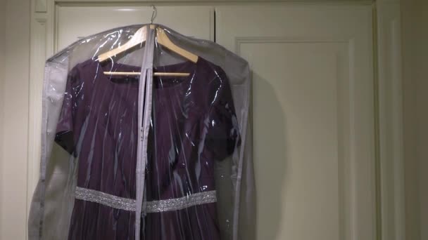 Paarse feestelijke vrouwen jurk hangt aan hanger op een garderobe in de kleedkamer. — Stockvideo