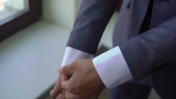 El hombre está sujetando un botón en una chaqueta gris. Hombre lleva un traje clásico. — Vídeos de Stock