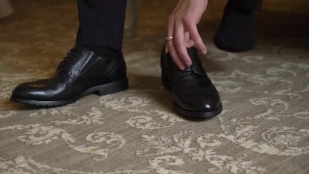 El hombre se pone los zapatos. Hombre en traje negro y calcetines con cordones en sus botas. — Vídeo de stock