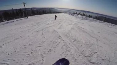 Karlı bir yamaçtan snowboard sporu yapan biri. Snowboardcu bir dağa biniyor..