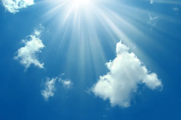 A blue sky with sun and clouds background.Shining sun on blue sky with clouds.Sunny sky background.Blue morning sky, bright sun rising and breaking through the white clouds.The bright midday sun lights up the blue sky and clouds.Sun in the blue sky.