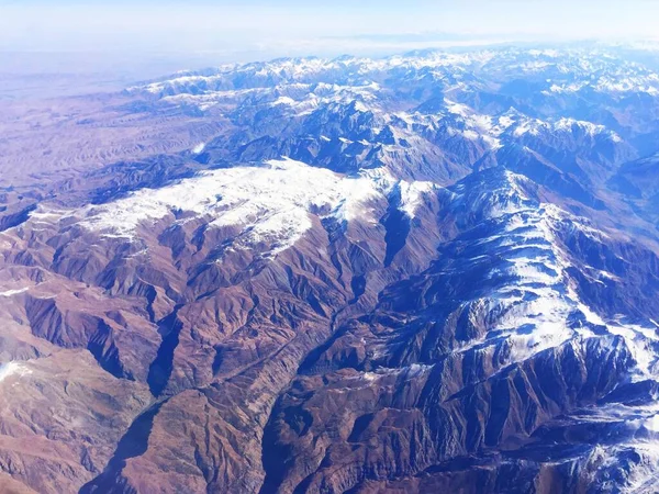Χιονισμένες βουνοκορφές της ράχης. Βόρεια χιονισμένα βουνά. από το παράθυρο του αεροπλάνου. Ορεινό τοπίο με χιονισμένες βουνοκορφές. Σμαραγδένιες λίμνες και απόκρημνα βουνά — Φωτογραφία Αρχείου