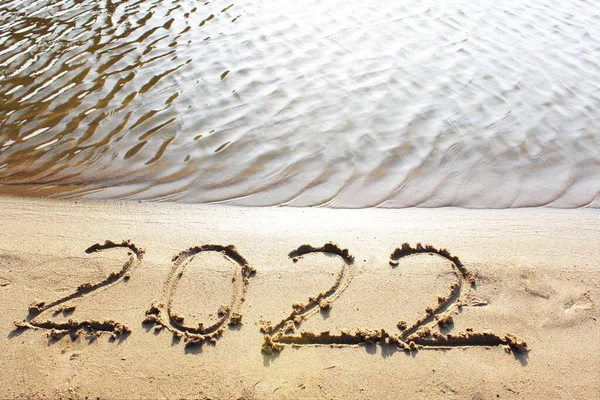 Ano Novo 2022. Mensagem escrita no fundo de uma praia de areia. Olá conceito para o próximo ano novo 2022. Natal de Ano Novo. com espaço de cópia para texto. Close-up e vista superior de brilhante — Fotografia de Stock