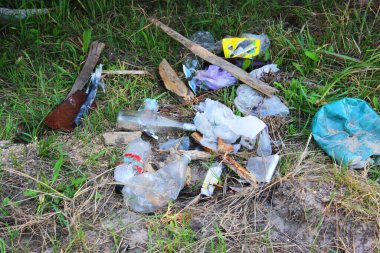 Plajda bir sürü çöp ve plastik torba bırakıldı. Diğer plastik eşyalarla birlikte. Çevre kirliliği kavramı. Kırışmış kırmızı teneke kutu kumsalda yatıyor... kirlilik...