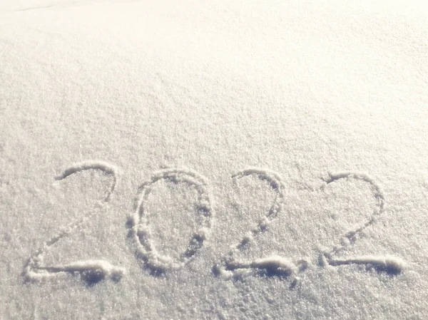 La inscripción en la nieve Nuevo 2022. Nochebuena, día de invierno con nevadas. copos de nieve voladores. hay nevadas brillantes del invierno en el suelo, humor del Año Nuevo afuera —  Fotos de Stock