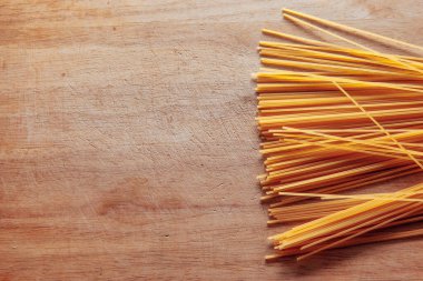 Kuru Spagetti Makarnası kesme tahtası arka planında gruplandırılmış. Tahtada pişmemiş makarna. Yüksek kaliteli fotoğraf.