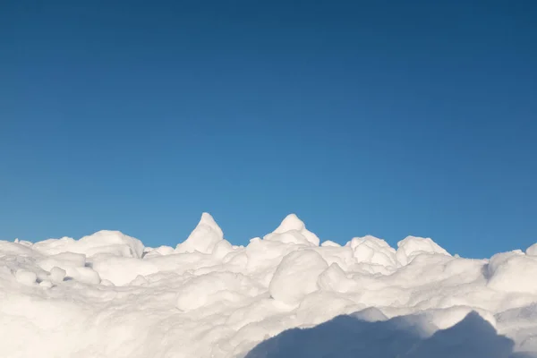 ふかふかの雪は、豪雪の後、丘や青空の周りに横たわっていました。ポスター、カレンダー、ポスト、スクリーンセーバー、壁紙、はがき、カード、バナー、カバー、ヘッダーのための青い空と雪のドリフト — ストック写真