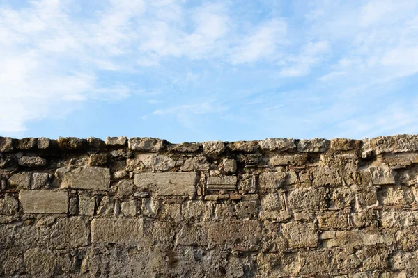 Stenen muur en blauwe lucht met witte wolken. Landschap achtergrond van baksteen muur en hemel voor poster, branding, kalender, veelkleurige kaart, banner, cover, post, header voor website. Hoge kwaliteit foto — Stockfoto