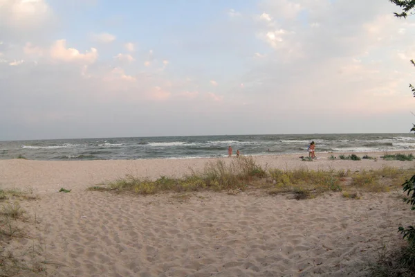 Seascape with children on sand beach on the sun day. Sea waves roll of the sandy shore. The sun sky with clouds. Seashore background for a post, screensaver, wallpaper, postcard, poster, banner, cover — Stock Photo, Image