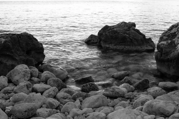 Tło kamiennej plaży ze skałami, zbliżenie. Szara kamienna plaża dla plakatu, kalendarza, poczty, wygaszacza ekranu, tapety, pocztówka, kartka, baner, okładka, strona internetowa. Czarno-białe wysokiej jakości zdjęcie — Zdjęcie stockowe