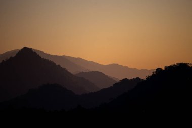 Sabahın ilk ışıklarıyla gökyüzünün görünüşü ve üst üste binen dağlar.
