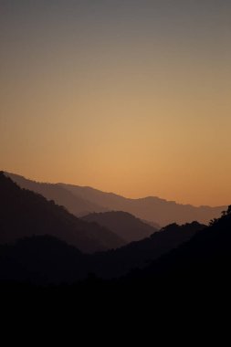 Sabahın ilk ışıklarıyla gökyüzünün görünüşü ve üst üste binen dağlar.