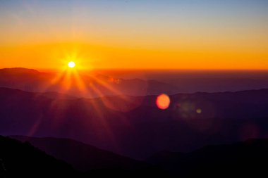 Sabahın ilk ışıklarıyla gökyüzünün görünüşü ve üst üste binen dağlar.