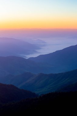 Sabahın ilk ışıklarıyla gökyüzünün görünüşü ve üst üste binen dağlar.