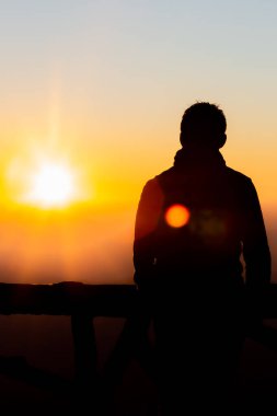 Gün batımı ve gün ışığı sisi olan siluet fotoğrafçı.