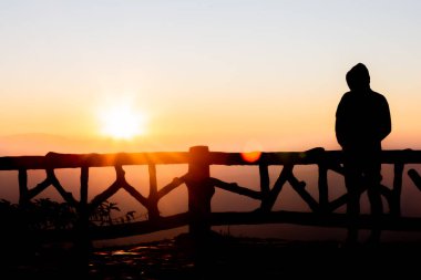 Gün batımı ve gün ışığı sisi olan siluet fotoğrafçı.