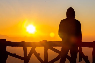 Gün batımı ve gün ışığı sisi olan siluet fotoğrafçı.