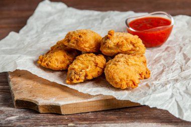 Baharatlı tavuk kanadı ve ahşap arka planda ketçap..