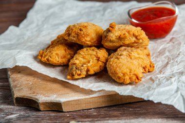 Baharatlı tavuk kanadı ve ahşap arka planda ketçap..