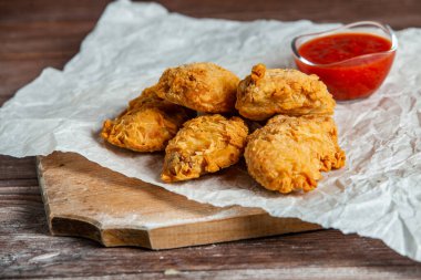 Baharatlı tavuk kanadı ve ahşap arka planda ketçap..