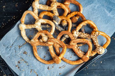 Taze ev yapımı yumuşak krakerler. Siyah arka planda tohumları olan farklı pişmiş simit türleri..