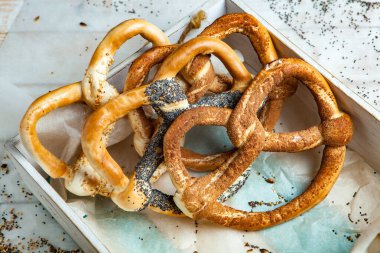 Taze ev yapımı yumuşak krakerler. Siyah arka planda tohumları olan farklı pişmiş simit türleri..