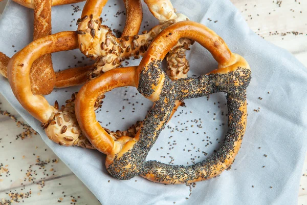 Taze ev yapımı yumuşak krakerler. Siyah arka planda tohumları olan farklı pişmiş simit türleri..