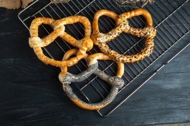 Taze ev yapımı yumuşak krakerler. Ahşap arka planda tohumları olan farklı türde fırınlanmış simit..