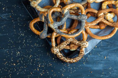 Taze ev yapımı yumuşak krakerler. Ahşap arka planda tohumları olan farklı türde fırınlanmış simit..