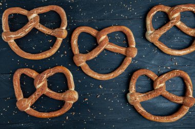 Taze ev yapımı yumuşak krakerler. Siyah arka planda tohumları olan farklı pişmiş simit türleri..