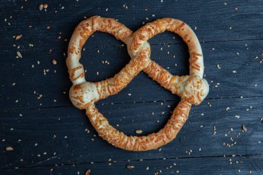 Taze ev yapımı yumuşak krakerler. Siyah arka planda tohumları olan farklı pişmiş simit türleri..