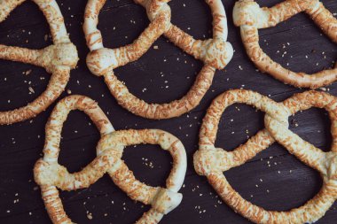 Taze ev yapımı yumuşak krakerler. Siyah arka planda tohumları olan farklı pişmiş simit türleri..