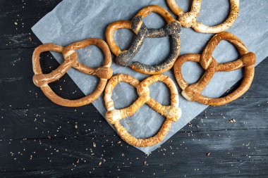 Taze ev yapımı yumuşak krakerler. Siyah arka planda tohumları olan farklı pişmiş simit türleri..