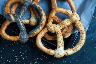 Taze ev yapımı yumuşak krakerler. Siyah arka planda tohumları olan farklı pişmiş simit türleri..