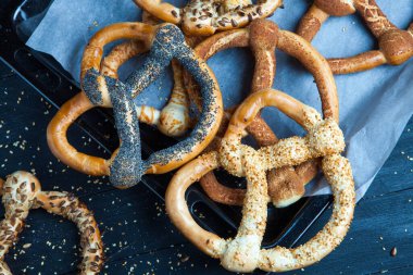 Taze ev yapımı yumuşak krakerler. Siyah arka planda tohumları olan farklı pişmiş simit türleri..