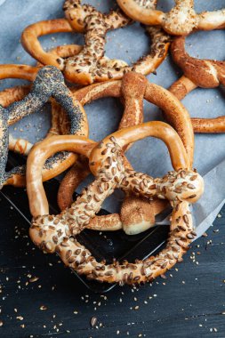 Taze ev yapımı yumuşak krakerler. Siyah arka planda tohumları olan farklı pişmiş simit türleri..