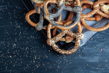 Taze ev yapımı yumuşak krakerler. Siyah arka planda tohumları olan farklı pişmiş simit türleri..