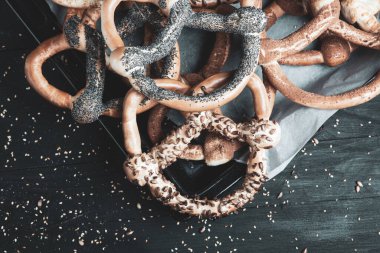 Taze ev yapımı yumuşak krakerler. Siyah arka planda tohumları olan farklı pişmiş simit türleri..