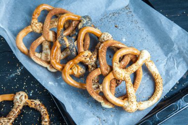 Taze ev yapımı yumuşak krakerler. Siyah arka planda tohumları olan farklı pişmiş simit türleri..