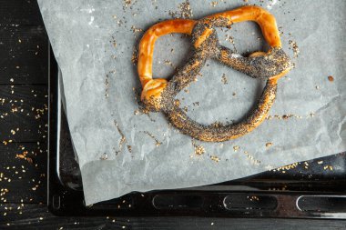 Taze ev yapımı yumuşak krakerler. Siyah arka planda tohumları olan farklı pişmiş simit türleri.
