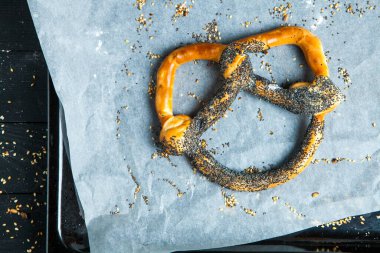 Taze ev yapımı yumuşak krakerler. Siyah arka planda tohumları olan farklı pişmiş simit türleri.