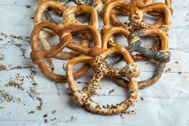 Taze ev yapımı yumuşak krakerler. Siyah arka planda tohumları olan farklı pişmiş simit türleri.