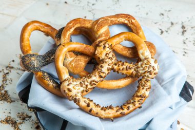 Taze ev yapımı yumuşak krakerler. Siyah arka planda tohumları olan farklı pişmiş simit türleri.