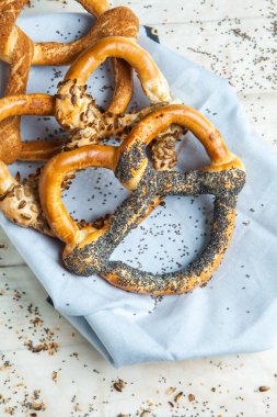 Taze ev yapımı yumuşak krakerler. Siyah arka planda tohumları olan farklı pişmiş simit türleri.