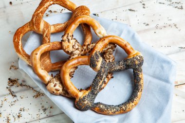 Taze ev yapımı yumuşak krakerler. Siyah arka planda tohumları olan farklı pişmiş simit türleri.