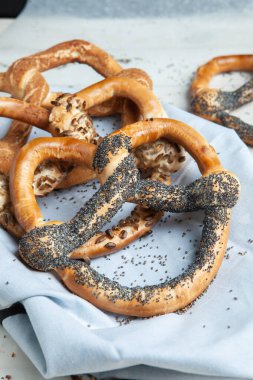 Taze ev yapımı yumuşak krakerler. Siyah arka planda tohumları olan farklı pişmiş simit türleri.