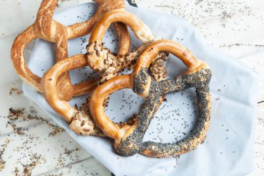 Taze ev yapımı yumuşak krakerler. Siyah arka planda tohumları olan farklı pişmiş simit türleri.